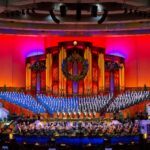 Coro do Tabernáculo da Praça do Templo se apresenta com orquestra durante concerto internacional.