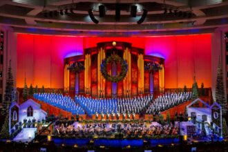 Coro do Tabernáculo da Praça do Templo se apresenta com orquestra durante concerto internacional.