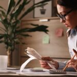 Pessoa analisando contas e calculadora, representando desafios da educação financeira no Brasil.