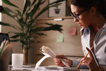 Pessoa analisando contas e calculadora, representando desafios da educação financeira no Brasil.