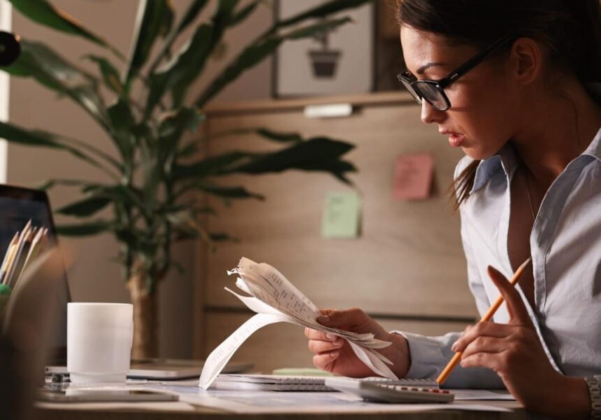 Pessoa analisando contas e calculadora, representando desafios da educação financeira no Brasil.