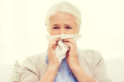 Pessoa idosa com sintomas gripais, com lenço no rosto.