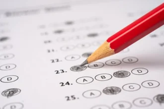 Caderno de prova de concurso público simboliza disputa judicial após erro no registro de inscrição em seleção para professores.