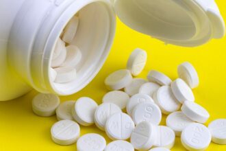 Comprimidos de antibiótico espalhados ao lado de frasco aberto