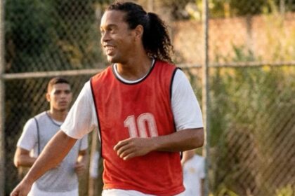 Ronaldinho Gaúcho em campanha publicitária segurando cerveja em cenário descontraído que remete a campo de futebol