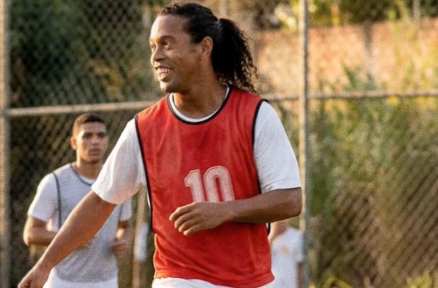 Ronaldinho Gaúcho em campanha publicitária segurando cerveja em cenário descontraído que remete a campo de futebol
