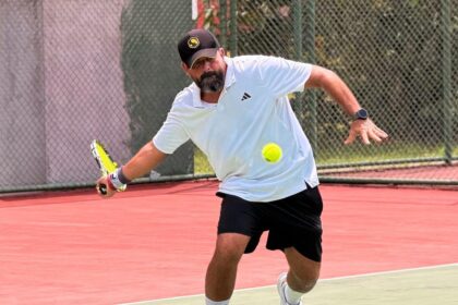 Homem jogando tênis em quadra durante partida com foco na movimentação e preparo físico