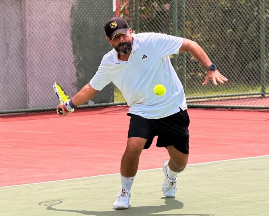 Homem jogando tênis em quadra durante partida com foco na movimentação e preparo físico