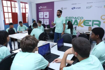 Alunos da rede pública participando de aula de robótica com notebooks em espaço maker educativo