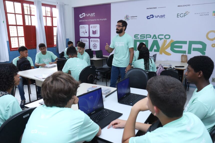 Alunos da rede pública participando de aula de robótica com notebooks em espaço maker educativo