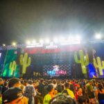 Palco de festival junino com iluminação colorida, público reunido e apresentações musicais durante evento cultural em Belém.