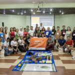 Grupo de jovens participantes do programa Raízes do Futuro posa em auditório durante evento de formação sobre bioeconomia, liderança comunitária e sucessão rural no Pará.