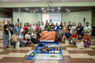 Grupo de jovens participantes do programa Raízes do Futuro posa em auditório durante evento de formação sobre bioeconomia, liderança comunitária e sucessão rural no Pará.