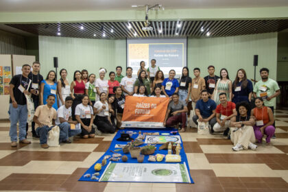 Grupo de jovens participantes do programa Raízes do Futuro posa em auditório durante evento de formação sobre bioeconomia, liderança comunitária e sucessão rural no Pará.