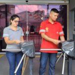 Mãe e filho passam juntos pela catraca de acesso de uma fábrica em Belém, usando uniforme da empresa durante a rotina de trabalho.